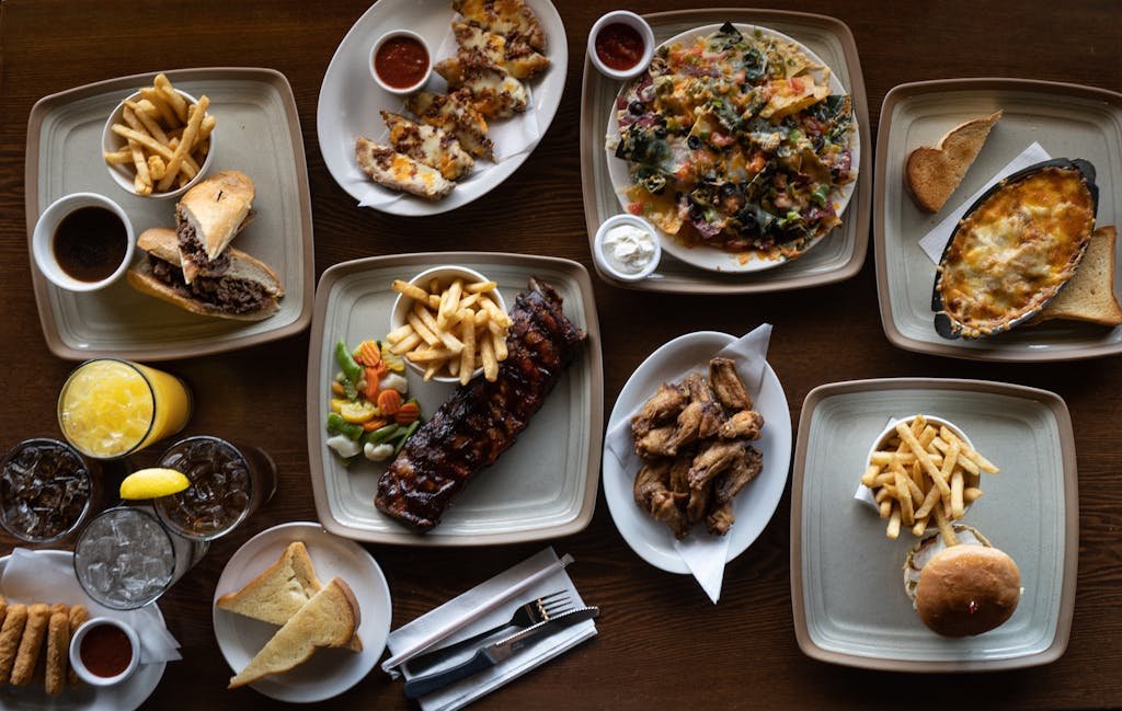 Flatlay of various delicious dishes including fries, ribs, and beverages.